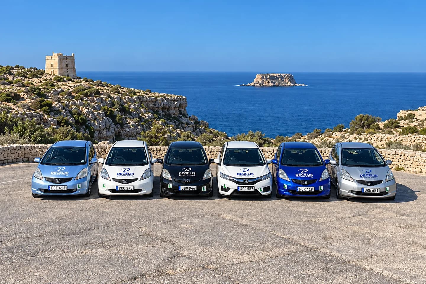 Six Decelis school cars parked in a row at Wied iż-Żurrieq, the watchtower and Filfla behind