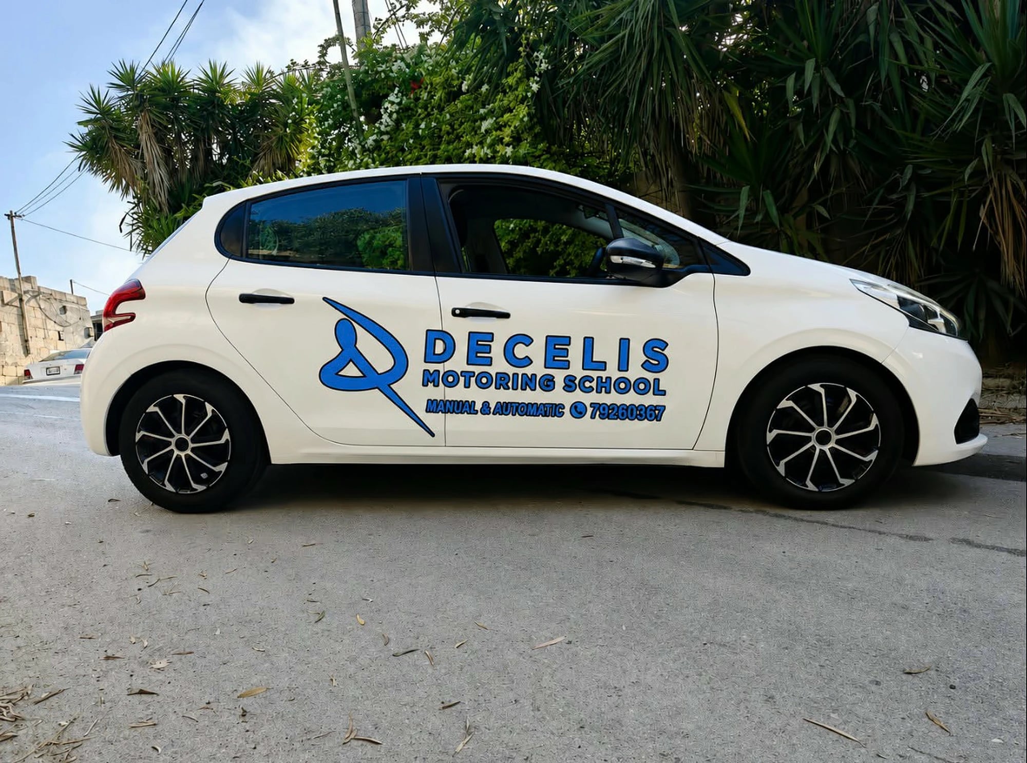 Our white Peugeot 208 with DECELIS MOTORING SCHOOL and Manual & Automatic in blue on its doors